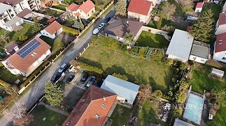 Velká zahrada s udržovaným trávníkem obklopená rodinnými domy, v klidné rezidenční oblasti s množstvím zeleně.