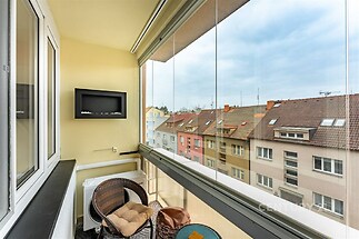 Zasklená lodžie s výhledem na městskou část, moderní design a pohodlné sezení.