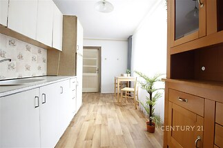 Světlá kuchyň s parketovou podlahou, velká okna poskytují dostatek světla, moderní dřevěný nábytek zajišťuje útulný vzhled.