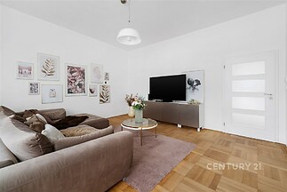 Světlý obývací pokoj, parketová podlaha, moderní výzdoba, pohodlná sedací souprava, minimalistický design, velká televize.