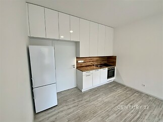 Moderní kuchyň, světlé parketové podlahy, bílá kuchyňská linka s dřevěným obložením, vestavěné spotřebiče, minimalistický styl