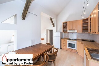 Kuchyň s dřevěným nábytkem, parketovou podlahou a moderními spotřebiči. Velká okna zajišťují světlost a prostornost, stylové trámy dodávají charakter.