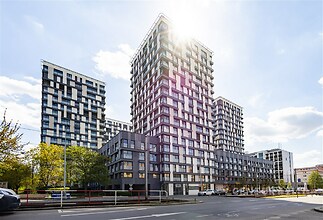 Moderní bytový komplex s velkými okny, fasádou z kvalitních materiálů a elegantním designem v atraktivní lokalitě městského centra