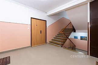 Vstupní hala s dlažbou, světlé stěny a dřevěné zábradlí poskytují moderní a čistý vzhled, ideální pro rekonstrukci nebo nové bydlení