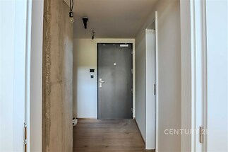 Moderní vstupní hala se stylovou betonovou stěnou, parketovou podlahou a kovovými dveřmi vytváří elegantní a útulný prostor