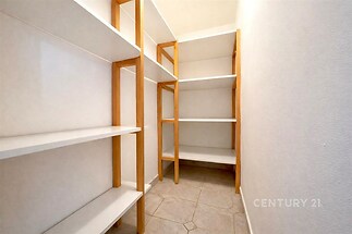 Úložný prostor s dlažbou a dřevěnými policemi, vhodný pro organizaci věcí, světlý interiér napomáhá snadné orientaci v prostoru.