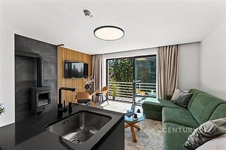 Světlý obývací pokoj s moderní krbovou kamnou, velkými okny a parketovou podlahou, ideální pro relaxaci v moderním stylu