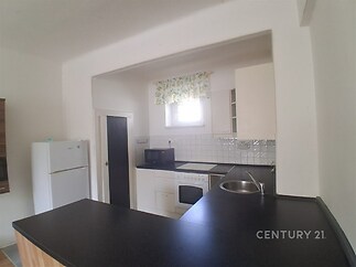 Moderní kuchyň s tmavou pracovní deskou, vestavěné spotřebiče, bílá dlažba na stěnách, světlé prvky.