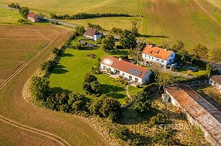 Letecký pohled na rozsáhlou vilu s červenou střechou, okolní velká zahrada, tiché venkovské prostředí, udržovaný trávník, slunná lokalita.