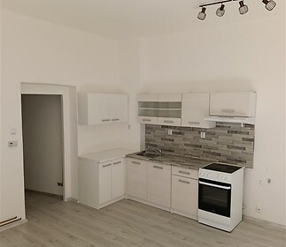 Moderní kuchyň s parketovou podlahou, světlými skříňkami a stylovým obkladem. Vhodná pro vytvoření příjemného kuchyňského prostoru.