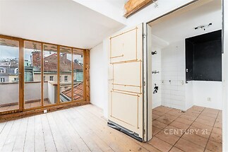 Světlá kuchyň s velkými okny, dřevěná podlaha, dlažba v prostoru na spotřebiče, vhodná k rekonstrukci, dobře osvětlená místnost.