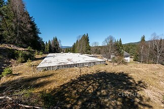 Prázdná stavební parcela s panoramatickým výhledem, obklopená lesy, ideální pro stavbu moderní chaty či rodinného domu.