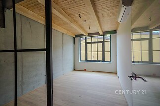 Pracovní prostor s dřevěným stropem, skleněnými příčkami a parketovou podlahou nabízí moderní design a velká okna pro přirozené světlo.