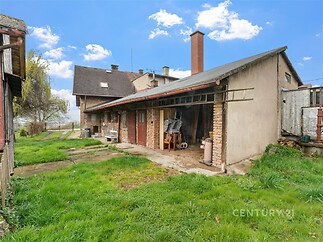 Zahrada s přístavkem, který má cihlové zdi a šikmou střechu, ideální pro skladování. Travnatá plocha nabízí prostor pro relaxaci.