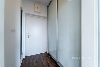Úzká chodba s parketovou podlahou, vestavěnými skříněmi a moderním stylovým designem.