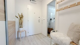 Vstupní hala s moderní dlažbou, světlým dřevem a vestavěným úložným prostorem, vybavena zrcadlem a stylovým nábytkem.