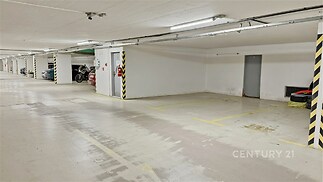 Podzemní parkovací stání s hladkou betonovou podlahou, zabezpečené prostředí, dostatek místa pro pohodlné parkování.