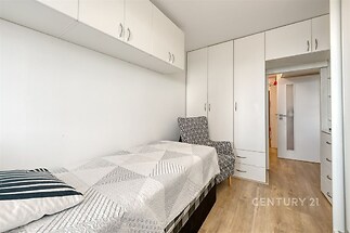 Útulná ložnice s vestavěnými skříněmi, parketová podlaha a moderní nábytek, poskytující dostatek úložného prostoru a stylovou atmosféru.