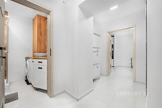 Světlá vstupní chodba s lesklou dlažbou, moderní interiér a vestavěné úložné prostory, spojuje koupelnu a další místnosti v bytě.