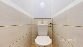 Kompaktní toaleta s dlažbou v neutrální barvě, moderní design a úsporný splachovací systém, vhodná pro menší prostory.