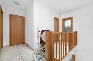 Světlá chodba s dlažbou a dřevěným zábradlím, zahrnující moderní bezbariérovou úpravu.