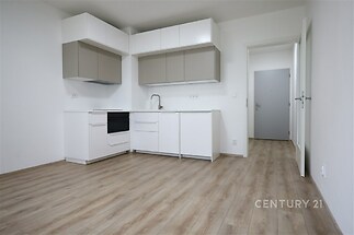 Moderní kuchyň s parketovou podlahou, světlé skříňky a vestavěné spotřebiče v nově rekonstruovaném bytě.