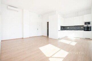 Světlý obývací pokoj s moderní kuchyní, parketová podlaha, velká okna, vestavěné spotřebiče, minimalistický design
