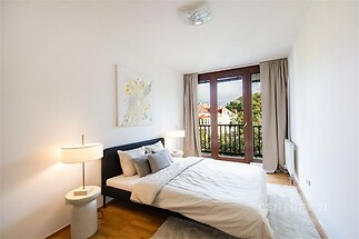 Prostorná ložnice s parketovou podlahou, velkými okny a moderním designem. Nabízí světlý interiér a výhled na klidnou lokalitu.
