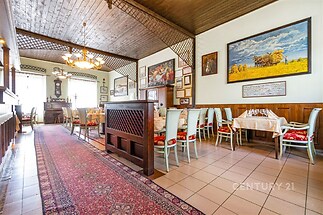 Restaurace s dlažbou, dřevěným obložením a vintage nábytkem, světlý interiér s velkými okny a ozdobným lustrem