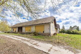 Starší rodinný dům s šikmou střechou, nacházející se na prostorném pozemku. Nemovitost vyžaduje rekonstrukci, ideální pro investici.
