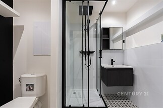 Moderní koupelna s černými doplňky, sprchovým koutem a stylovými obklady. Nově zrekonstruovaná, nabízí elegantní a praktický design.