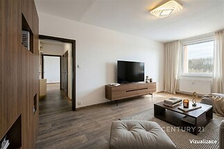 Světlý obývací pokoj s dřevěnou podlahou, velká okna a moderní nábytek.