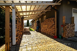 Krytá terasa s kamennou dlažbou, stěny obložené dřevem, moderní střecha z průhledného polykarbonátu, prostor vhodný pro úložný prostor.