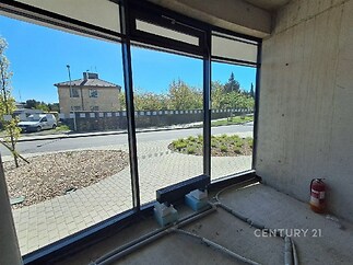 Prázdný komerční prostor, velká prosklená stěna, výhled na ulici, betonová stěna, vhodné pro obchodní účely, světlý interiér