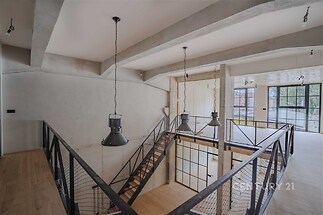 Útulné schodiště s dřevěnými schody, moderní kovové zábradlí a velká okna, kombinace industriálního a moderního stylu, světlý interiér.