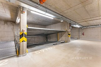 Podzemní parkovací místo s betonovými stěnami, moderní osvětlení, automatizovaný parkovací systém.