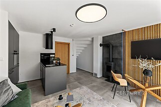 Moderní obývací pokoj s dlažbou, krbovými kamny a světlým interiérem, doplněný stylovým nábytkem a velkými okny pro dostatek přirozeného světla