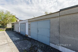 Řadová garáž s plechovými vraty, situovaná na asfaltové ploše. Garáž v původním stavu, vhodná pro parkování či skladování.