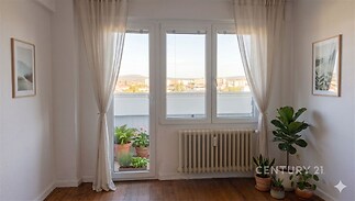 Světlý obývací pokoj s parketovou podlahou, velkými okny a moderním designem.