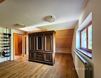 Prostorná ložnice s dřevěnou podlahou, vestavěnou skříní a velkými okny, které poskytují dostatek světla.