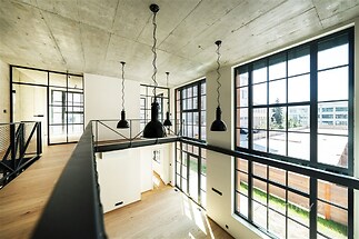 Mezonet s velkými okny, moderním designem a dřevěnou podlahou, nabízí světlý prostor s výhledem, kovovými prvky a vysokými stropy.