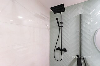 Moderní sprchový kout s matnou černou baterií, elegantní dlaždice ve světlém odstínu, luxusní design koupelny