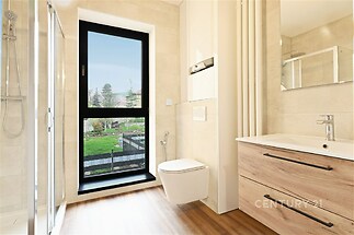 Moderní koupelna s dřevěnou podlahou, velkým oknem a světlými obklady nabízí elegantní a světlý prostor.