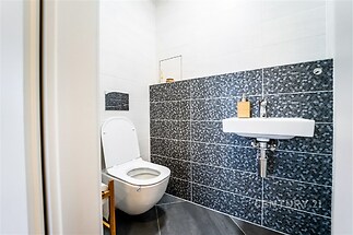 Moderní koupelna s keramickými obklady, závěsnou toaletou a elegantním umyvadlem, jednoduchý design a kvalitní povrchové materiály