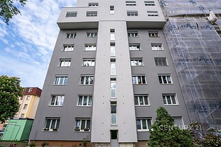 Šedá fasáda bytového domu, moderní renovace, vícepatrová budova, nová okna, zateplená stěna, klidná rezidenční oblast.