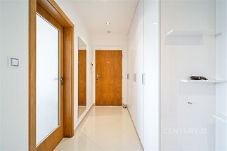 Světlá předsíň s dlažbou, moderní vestavěné skříně a dřevěné dveře, minimalistický design a čisté linie pro elegantní vzhled.