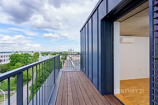 Balkon s dřevěnou podlahou nabízí panoramatický výhled, moderní konstrukce a přístup z interiéru s parketovou podlahou zajišťuje komfort.
