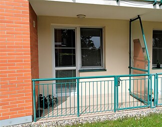 Přízemní balkon s bezpečnostním zábradlím, plastová okna, dlažba, vhodný pro relaxaci s výhledem do zahrady, cihlová fasáda budovy