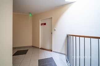 Průchod s dlažbou, dveře bytu 505, moderní styl, neutrální barvy, bezpečnostní osvětlení na stropě.