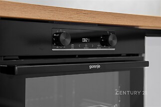 Moderní kuchyňská linka s vestavěnou troubou Gorenje, černý design a dřevěná pracovní deska, ideální pro moderní bydlení